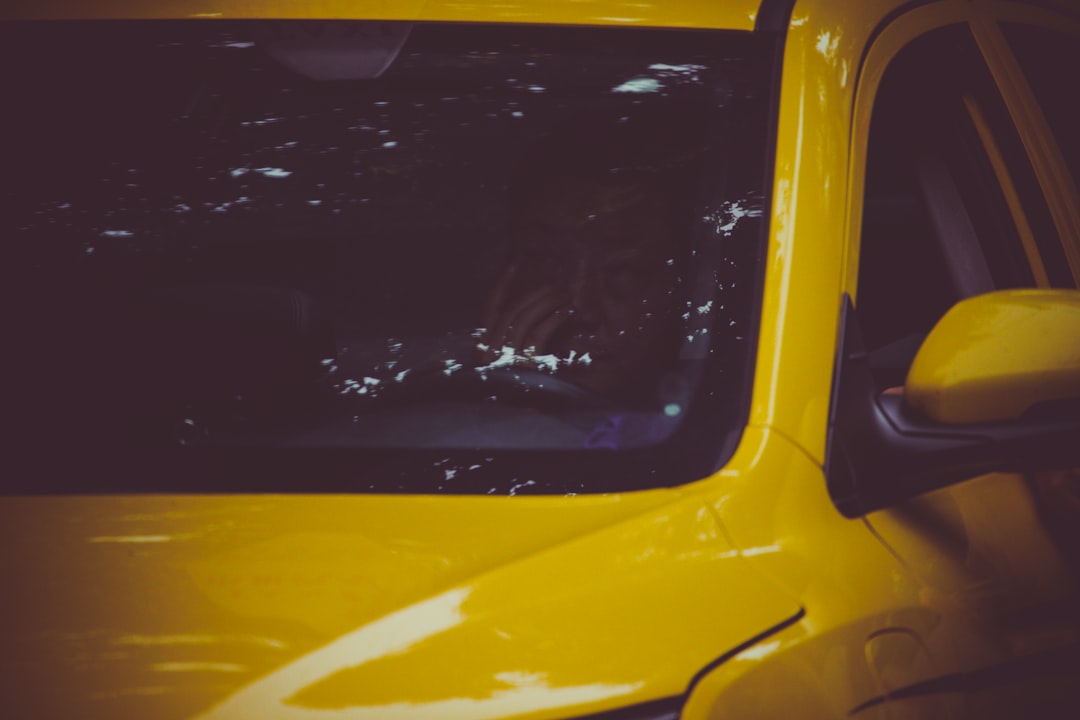 Close-up of a yellow car's windshield and side mirror.
